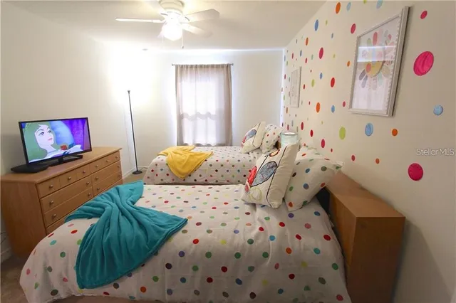 a bedroom with a bed and a flat tv screen on the dresser