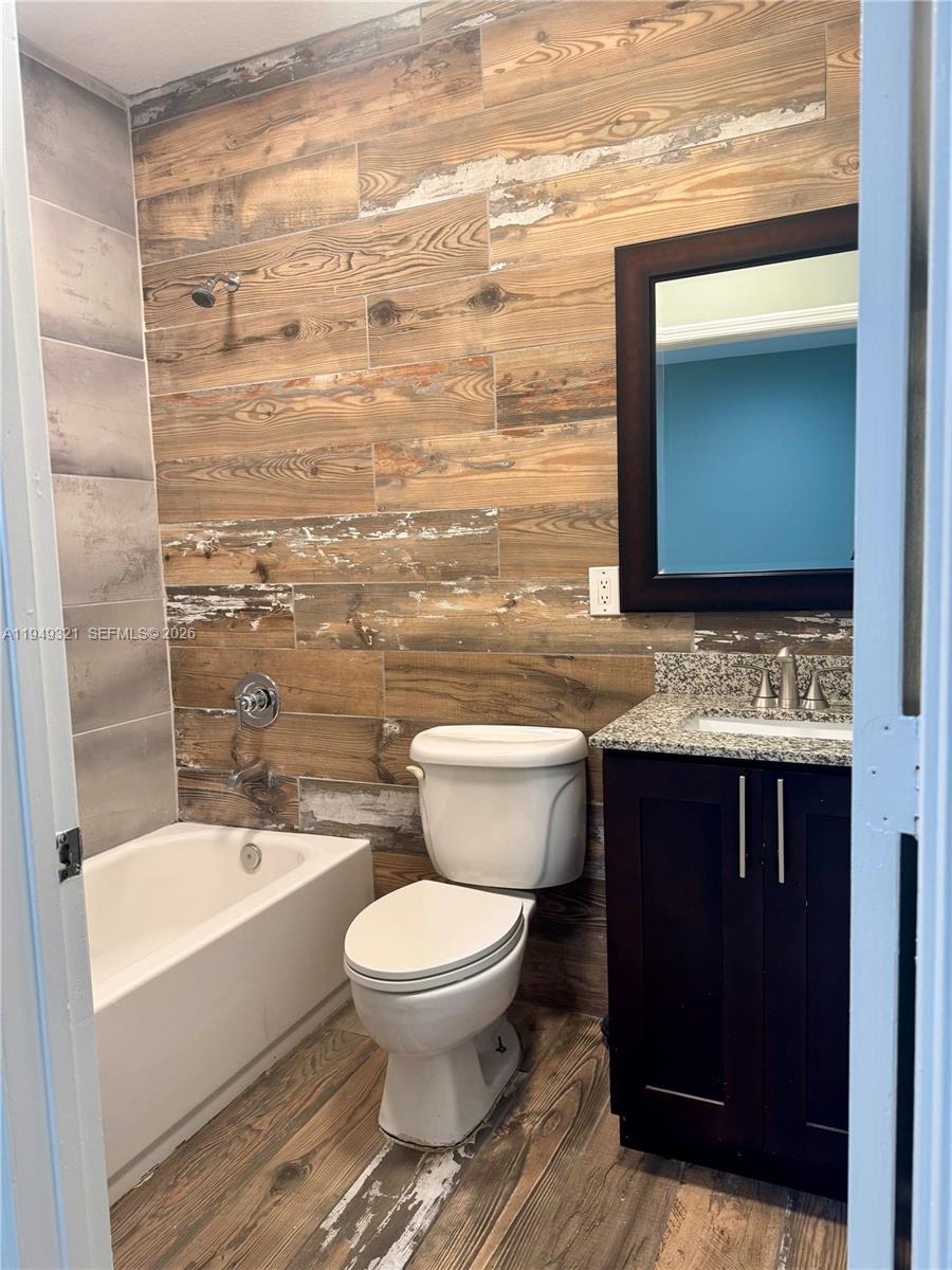 603 Northwest 97th Street, Unit 603 Miami, FL 33150 - Photo 20 of 28 a bathroom with a granite countertop toilet a sink and bathtub