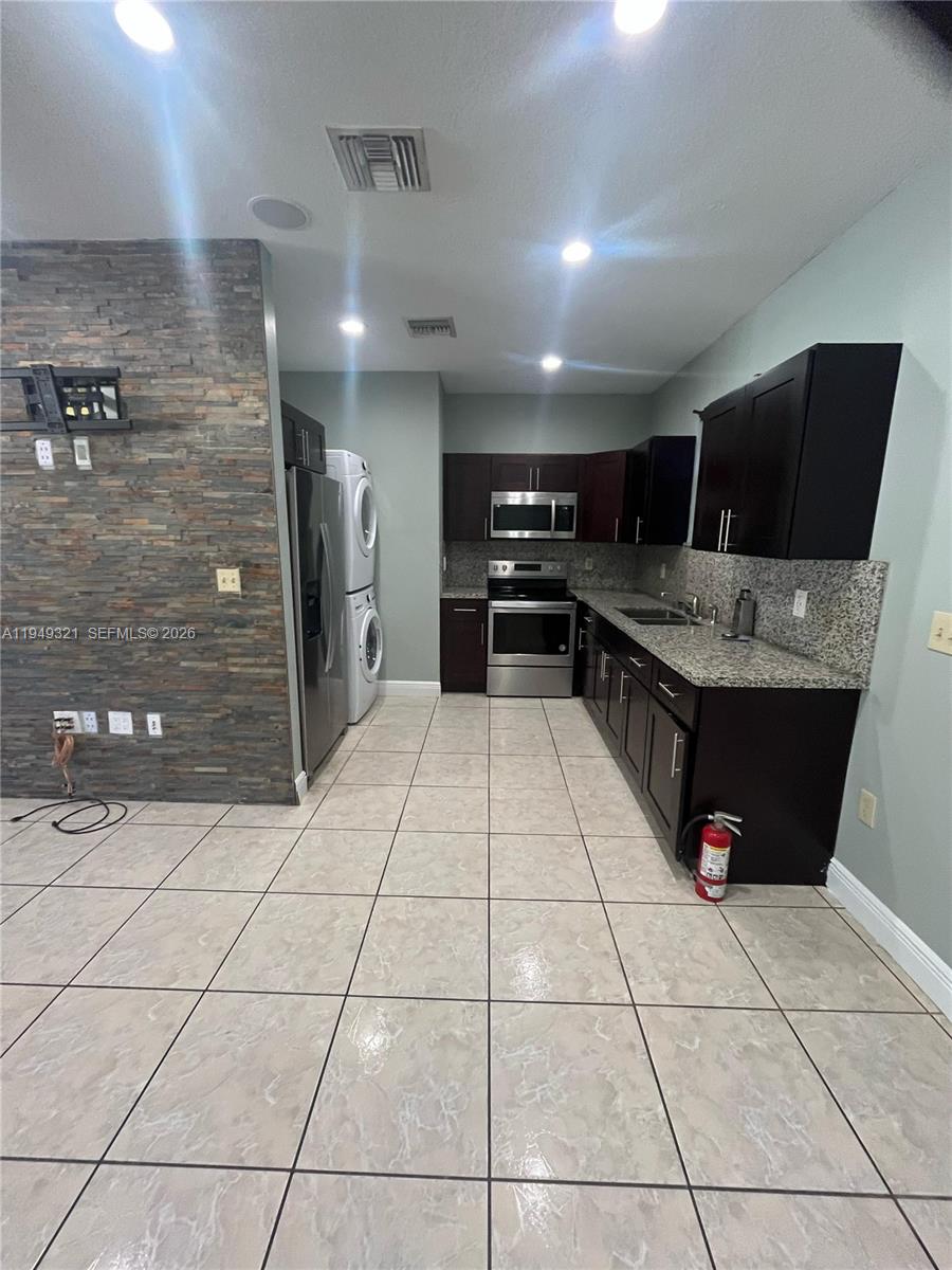 603 Northwest 97th Street, Unit 603 Miami, FL 33150 - Photo 5 of 28 a kitchen with stainless steel appliances kitchen island granite countertop a refrigerator and a stove top oven