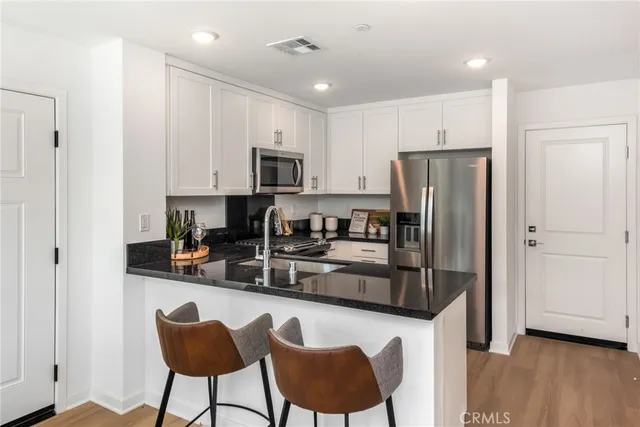 a kitchen with stainless steel appliances granite countertop a refrigerator a stove a sink dishwasher and a refrigerator with wooden floor