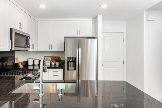 a kitchen with stainless steel appliances granite countertop a refrigerator and cabinets