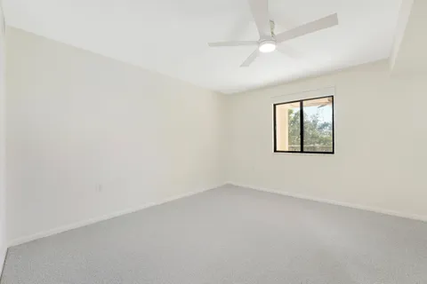 an empty room with a window and a fan