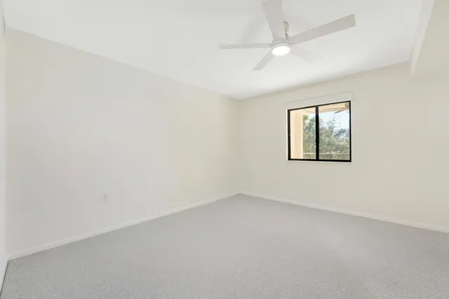 an empty room with a window and a fan