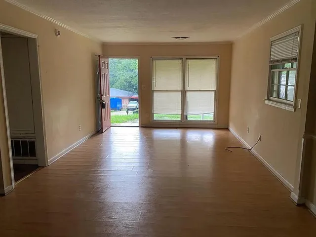 a view of an empty room with wooden floor and a window