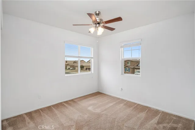 an empty room with a window and a fan