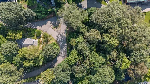 an aerial view of residential house with outdoor space and trees all around