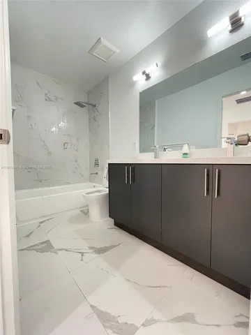 a bathroom with a bathtub shower sink mirror vanity and toilet