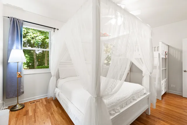 a view of a bedroom with wooden floor and a window