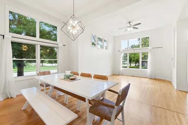 a dining room with wooden floor a chandelier a table and chairs