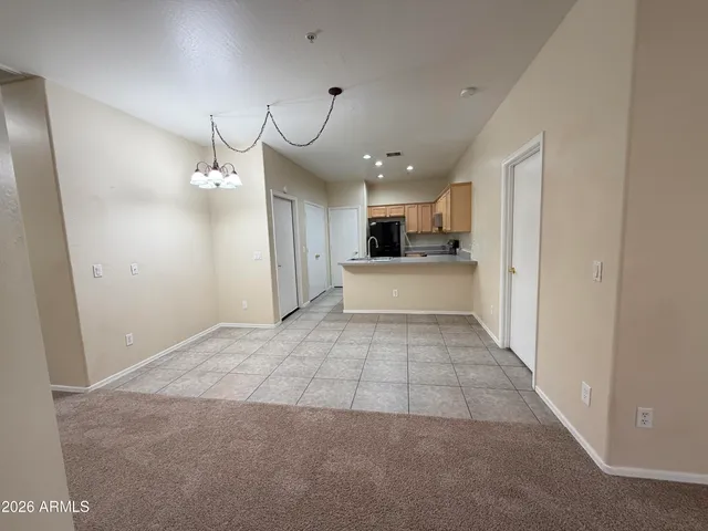 an empty room with a kitchen and a chandelier fan