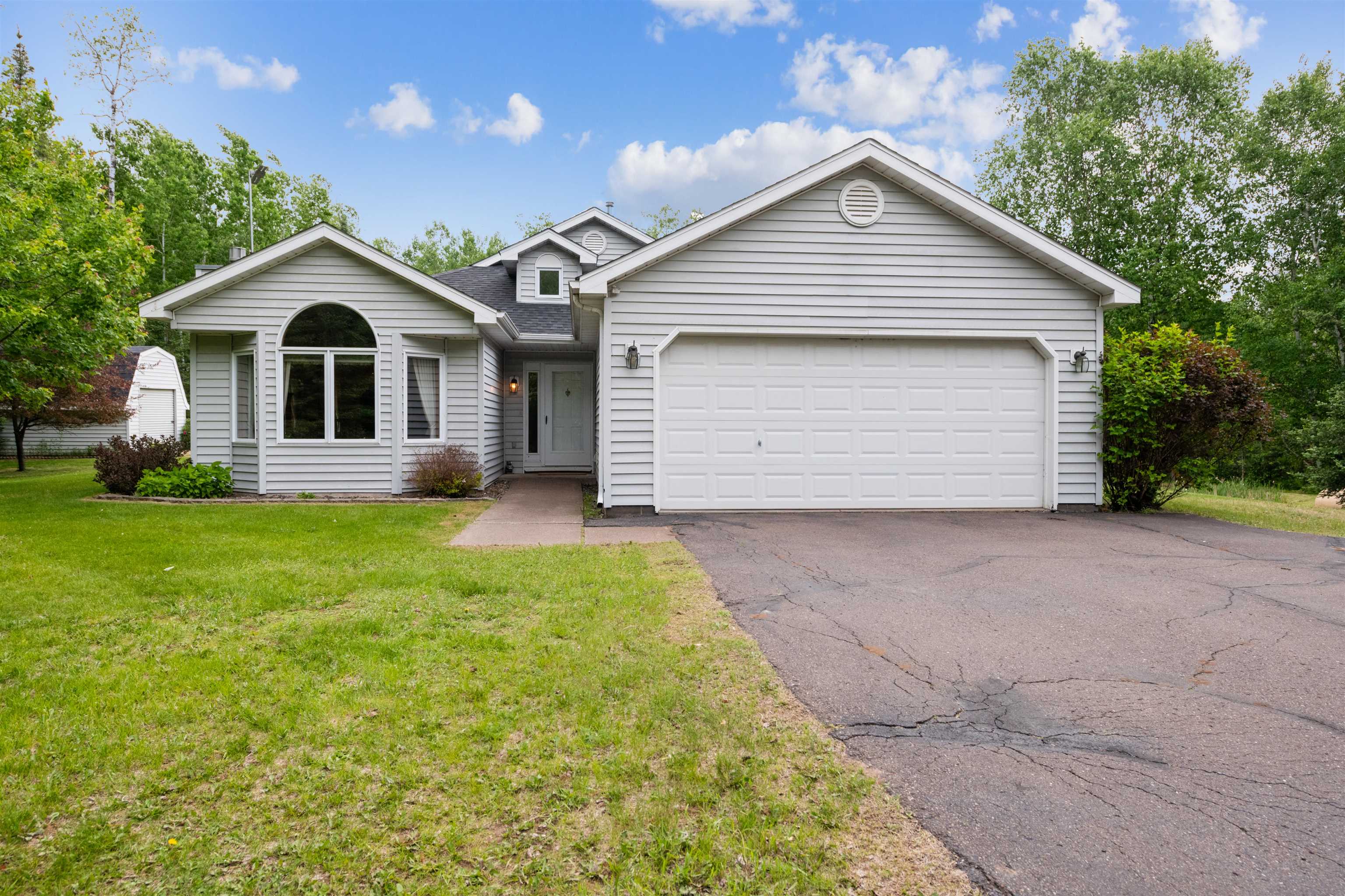 View of front of home featuring asphalt driveway, roof with shingles, a front yard, and an attached garage