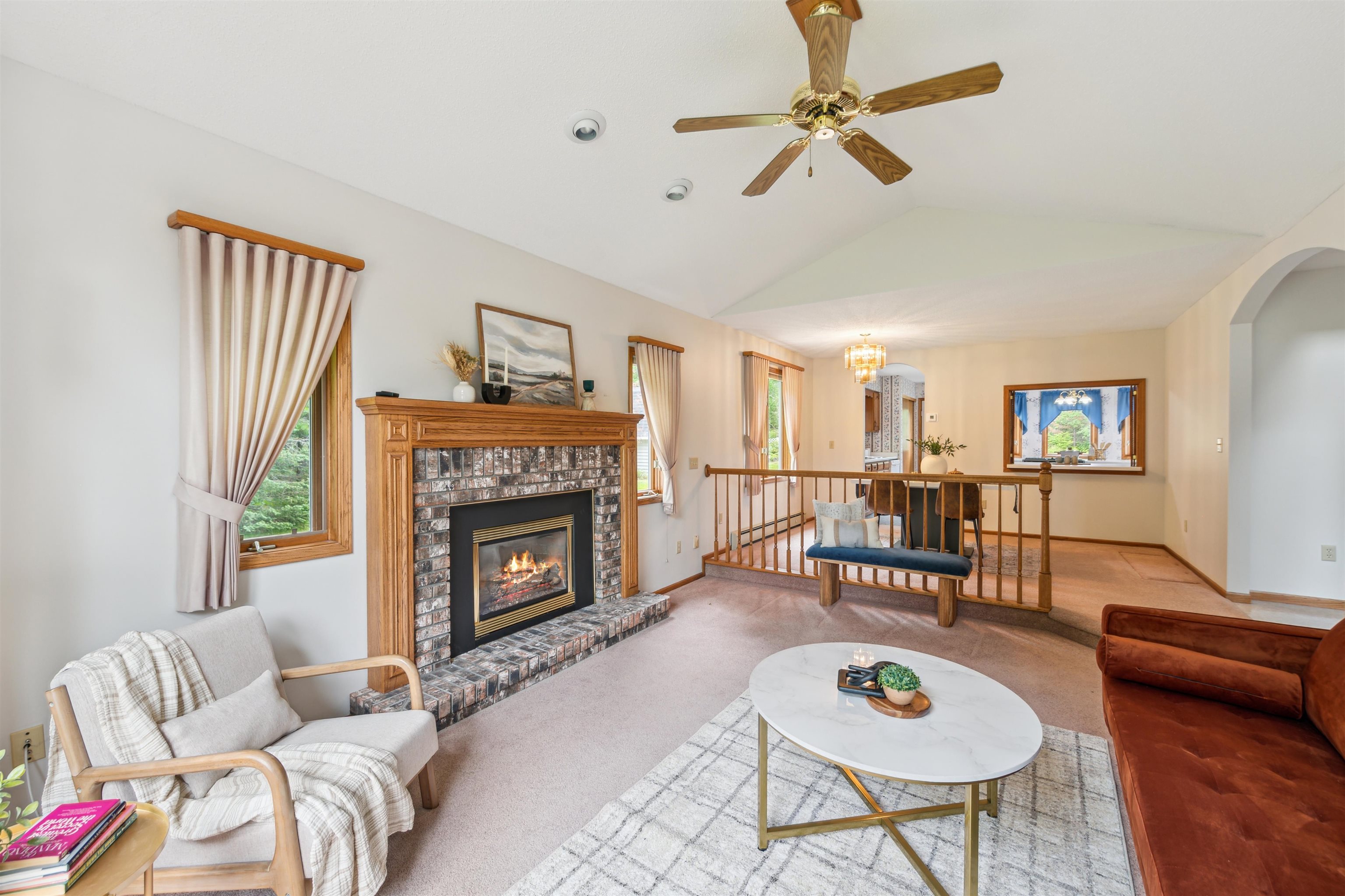 5948 Lavaque Road Duluth, MN 55803 - Photo 4 of 22 Carpeted living area featuring vaulted ceiling, a ceiling fan, arched walkways, and a fireplace