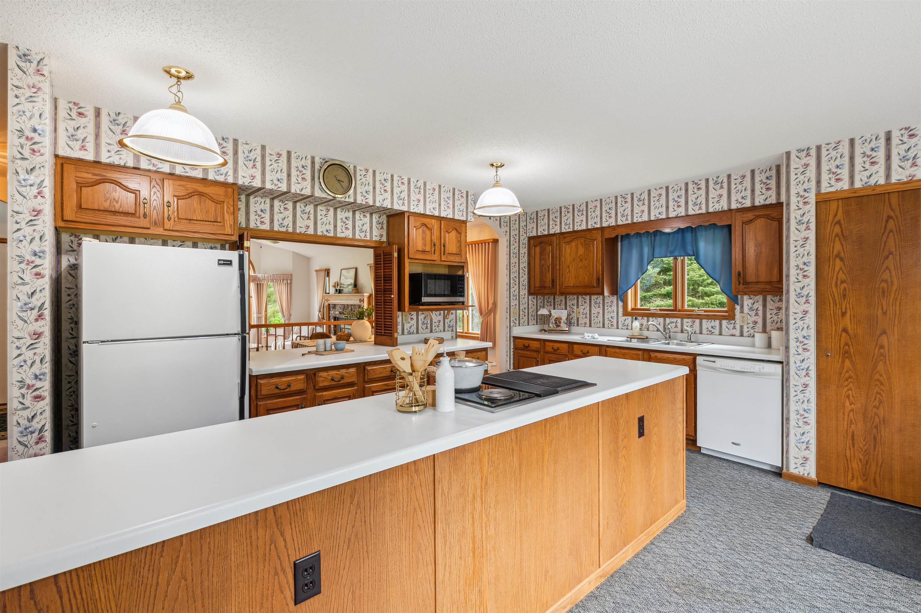 5948 Lavaque Road Duluth, MN 55803 - Photo 8 of 22 Kitchen featuring white appliances, wallpapered walls, light countertops, brown cabinets, and carpet