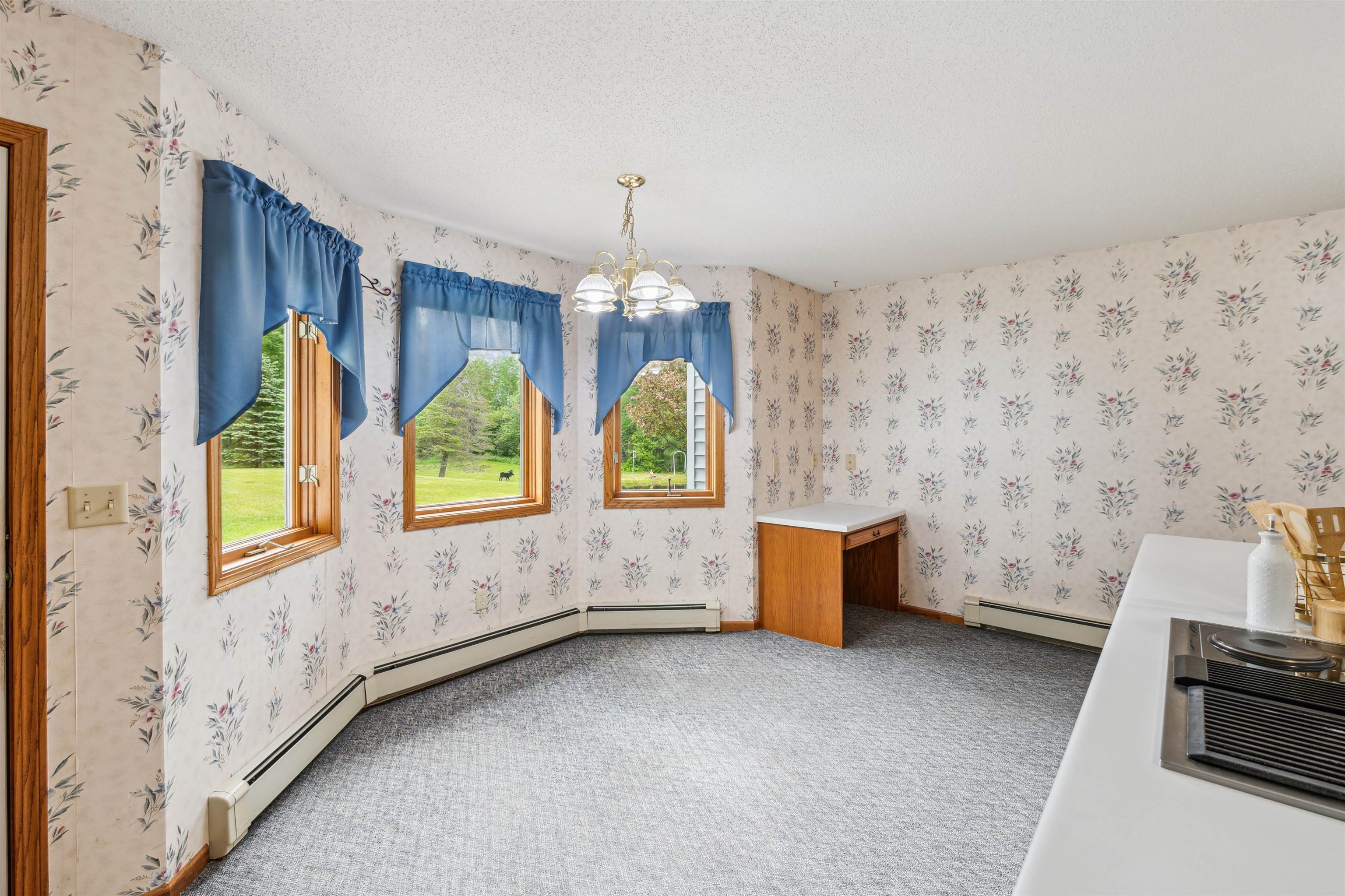 5948 Lavaque Road Duluth, MN 55803 - Photo 9 of 22 Unfurnished dining area featuring a baseboard heating unit, wallpapered walls, carpet, a chandelier, and a textured ceiling