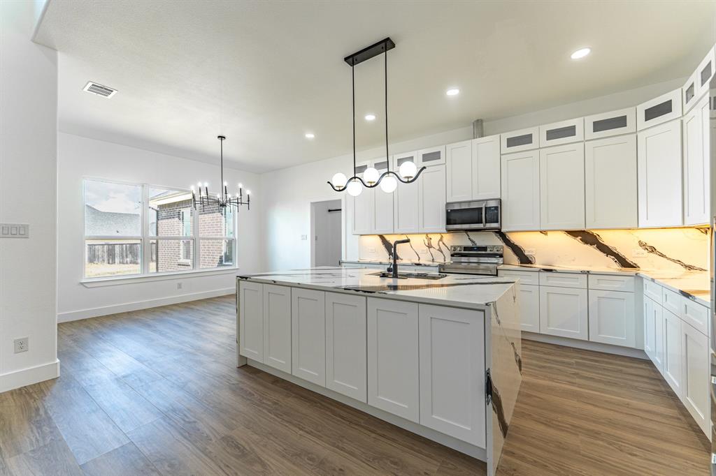 2147 Heath Street Sulphur Springs, TX 75482 - Photo 4 of 40 a large kitchen with kitchen island white cabinets and wooden floor