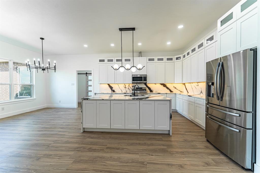 2147 Heath Street Sulphur Springs, TX 75482 - Photo 5 of 40 a kitchen with kitchen island granite countertop a refrigerator oven a sink dishwasher and a refrigerator with wooden floor