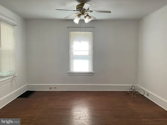 an empty room with wooden floor windows and fan