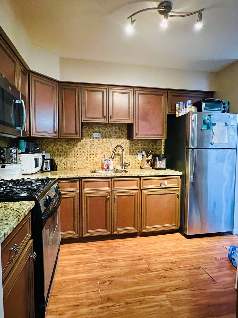 4624 North Commons Drive, Unit 307 Chicago, IL 60656 - Photo 11 of 18 a kitchen with granite countertop a refrigerator stove top oven and sink