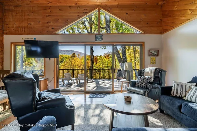 a living room with furniture a floor to ceiling window and a flat screen tv