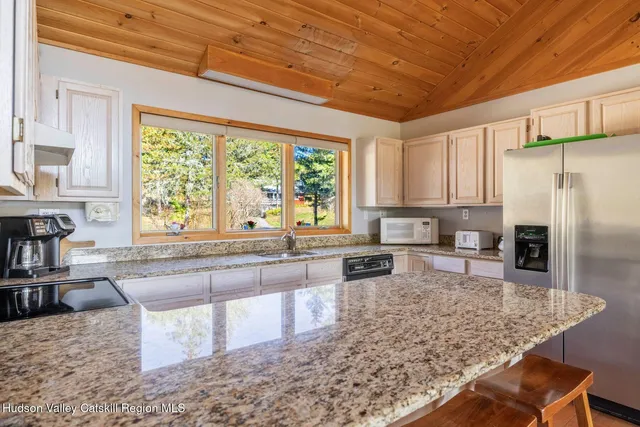 a large kitchen with kitchen island granite countertop wooden cabinets a granite counter top and a large window