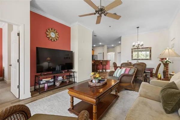 a kitchen with stainless steel appliances kitchen island granite countertop a refrigerator a stove a sink a dining table and chairs with wooden floor