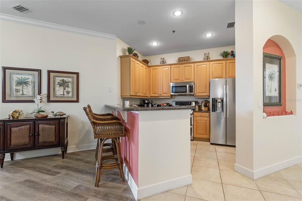 35 Ocean Crest Way, Unit 1124 Palm Coast, FL 32137 - Photo 10 of 81 a kitchen with stainless steel appliances kitchen island granite countertop a refrigerator a stove a sink a dining table and chairs with wooden floor