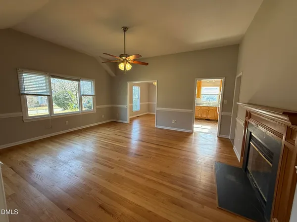 an empty room with wooden floor fireplace and windows