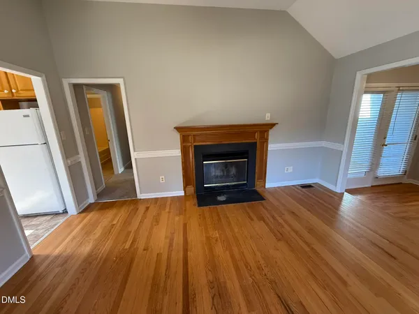a view of empty room with wooden floor and fireplace