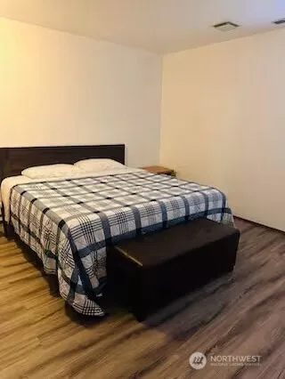 a bedroom with a bed and wooden floor