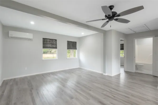 a view of an empty room with a window and wooden floor