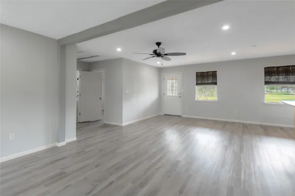 a view of an empty room with a window and wooden floor