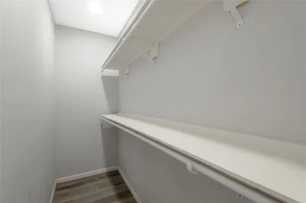 an empty room with wooden floor chandelier fan and windows