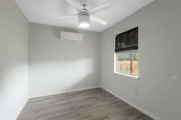 an empty room with a window and wooden floor