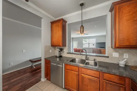 a kitchen with stainless steel appliances granite countertop a sink a stove and a wooden floor