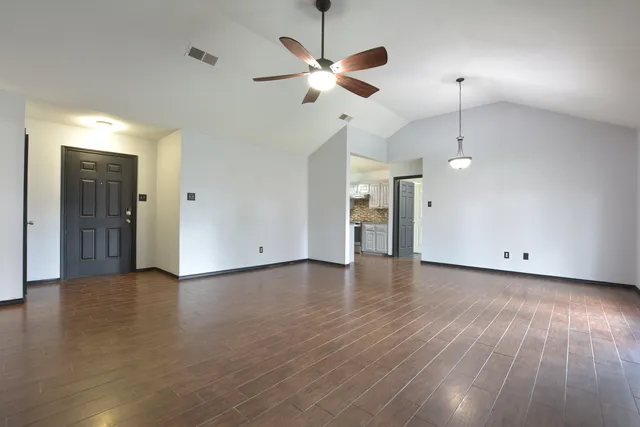 an empty room with wooden floor and a ceiling fan