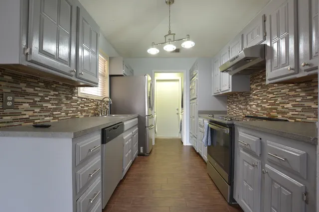 a kitchen with stainless steel appliances granite countertop wooden cabinets and a sink