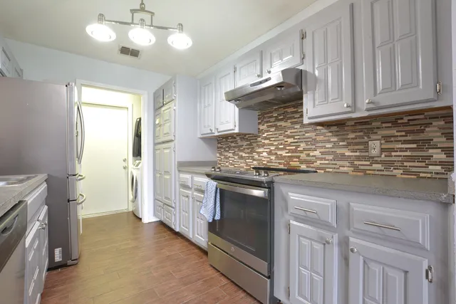 a kitchen with stainless steel appliances granite countertop a sink a stove and a refrigerator