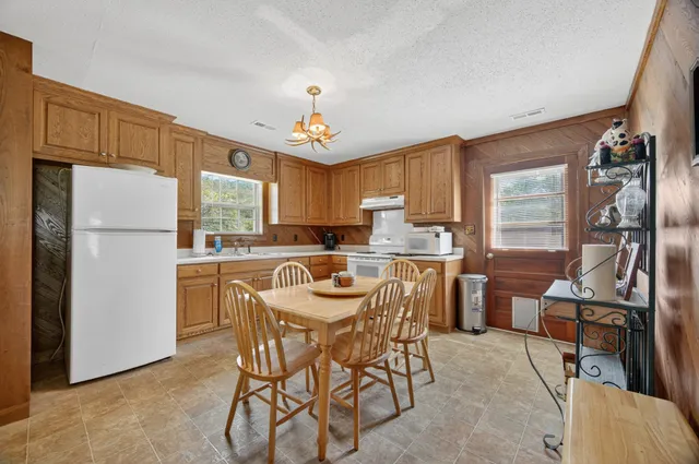 a kitchen with stainless steel appliances a refrigerator a stove a sink dishwasher and a dining table with wooden cabinet