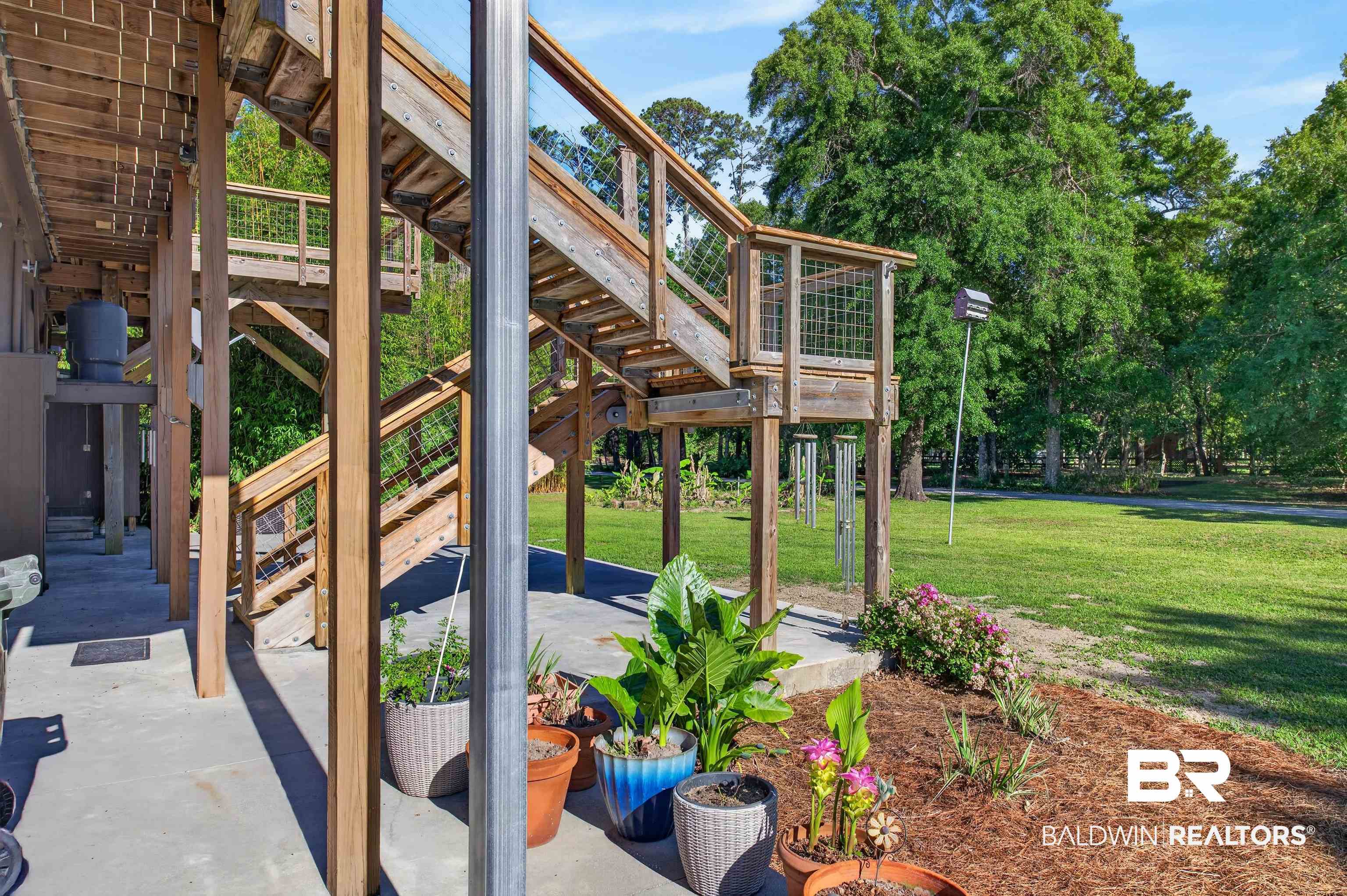 9624 North Bay Street Foley, AL 36535 - Photo 46 of 59 Elevated wood decking with exposed support beams, featuring a multi-level staircase with wire infill railings