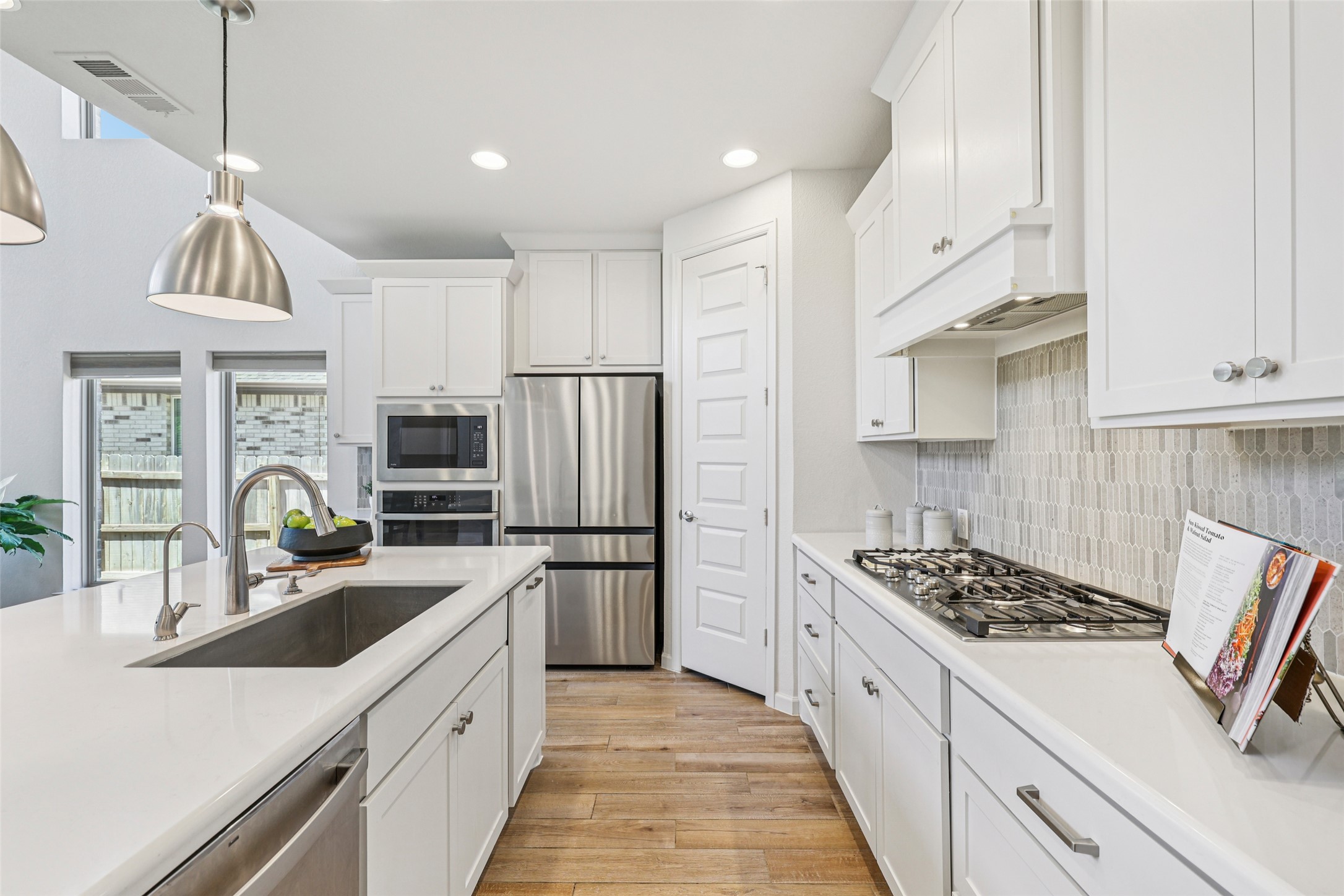 1140 Bryson Rdg Trail Leander, TX 78641 - Photo 8 of 39 The kitchen features white cabinetry, stainless steel appliances, a gas cooktop, and a spacious island with a sink