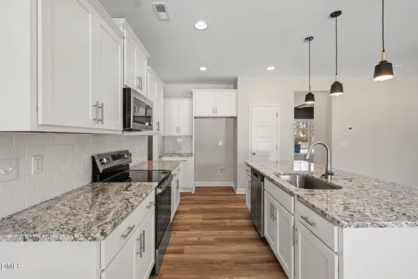 a kitchen with stainless steel appliances a dining table chairs stove top oven and cabinets