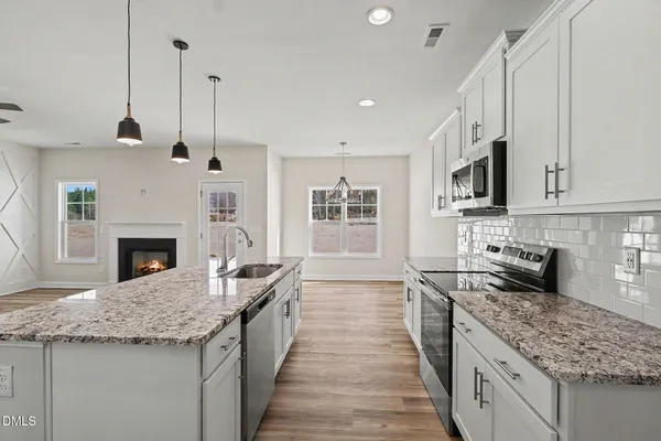 a view of a livingroom with a fireplace a ceiling fan and wooden floor