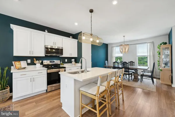 a kitchen with stainless steel appliances kitchen island granite countertop a stove a refrigerator a kitchen island a dining table and chairs with wooden floor