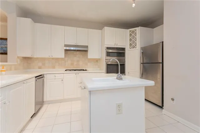 a kitchen with a sink a stove a refrigerator and white cabinets