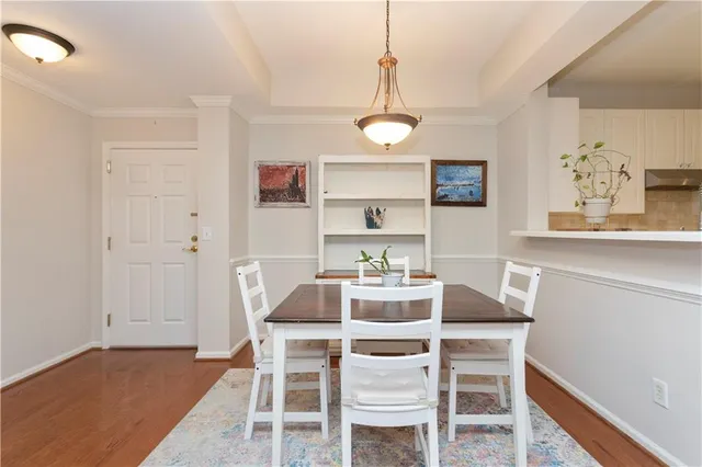 a dining room with wooden floor a chandelier a wooden table and chairs