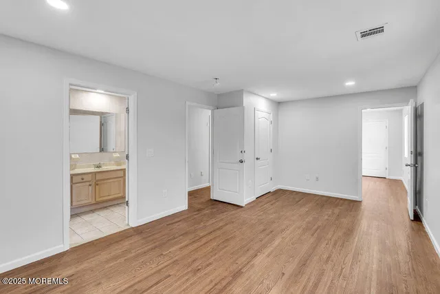 a view of an empty room with a kitchen and wooden floor