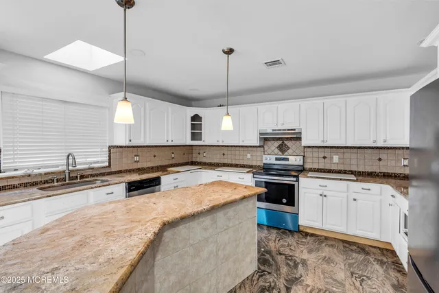 a kitchen with stainless steel appliances granite countertop a sink a stove a center island a stove and cabinets