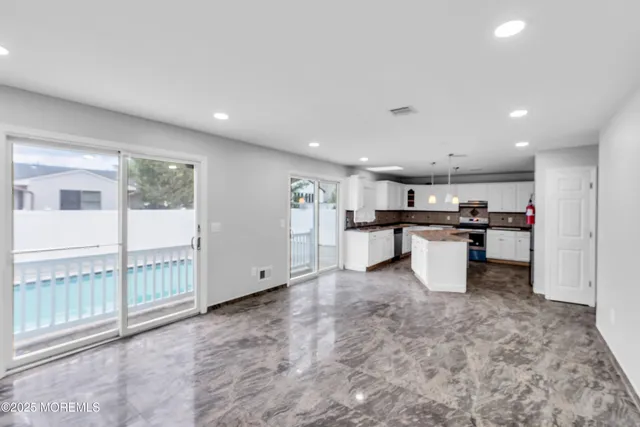 a kitchen with stainless steel appliances kitchen island granite countertop a refrigerator and a sink