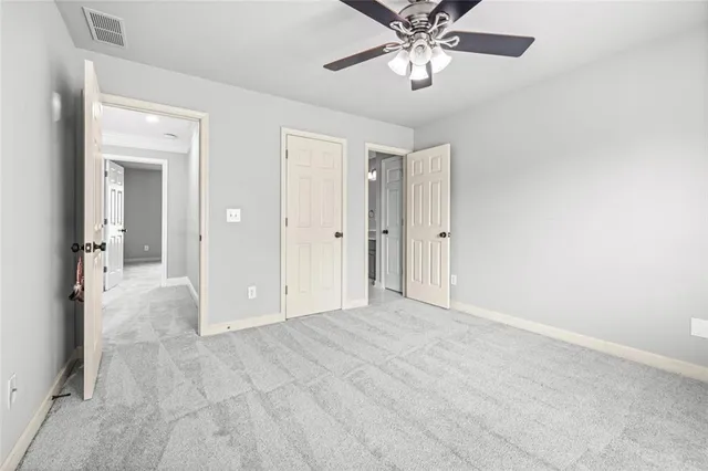 a view of an empty room and chandelier fan