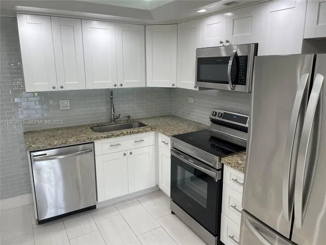 a kitchen with stainless steel appliances granite countertop a stove top oven microwave and refrigerator